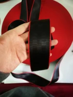 Hand holding high-quality black and red custom car seatbelt webbing from Roh Accessoires Morocco